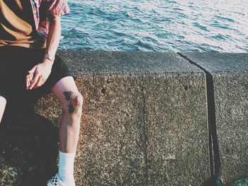 Low section of woman sitting by sea