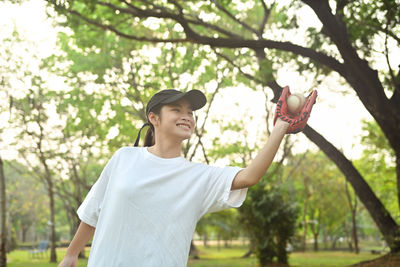 Portrait of smiling young woman standing against trees