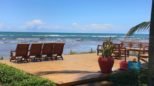 Chairs and table at beach against sky