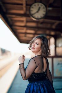 Portrait of young woman standing against building
