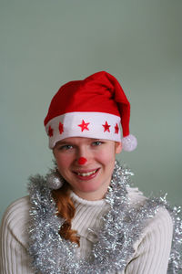 Close-up portrait of smiling woman in santa hat against wall