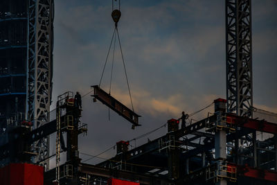 Low angle view of cranes against sky at dusk