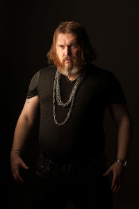 Portrait of mature man standing against black background