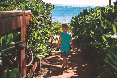 Full length of young woman standing by plants