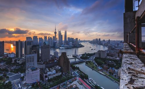 High angle view of cityscape and river against cloudy sky during sunset