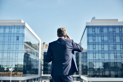 Rear view of man standing against building in city