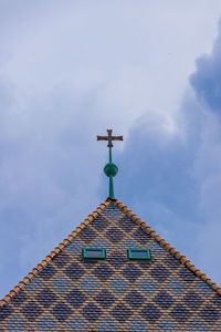 Low angle view of cross on roof of building against sky