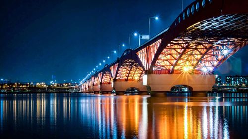 Illuminated bridge over river at night