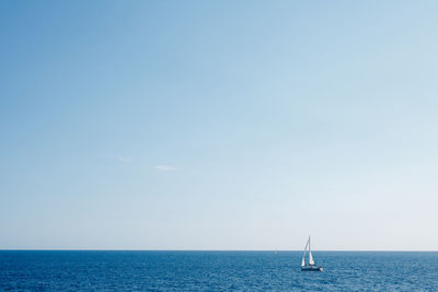 Sailboat sailing in sea against clear sky