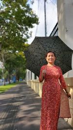 Portrait of smiling woman holding umbrella standing outdoors