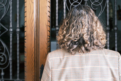 Rear view of woman looking through window