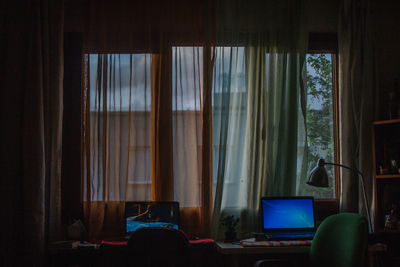 Digital laptops on table by window at home