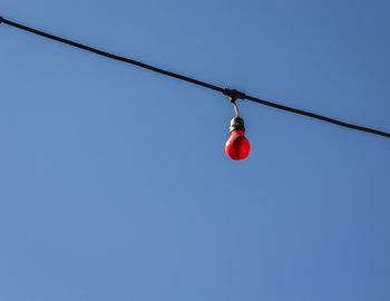 Low angle view of red hanging against clear blue sky