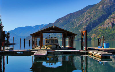 Boat by pier at lake chelan against mountains and clear blue sky on sunny day