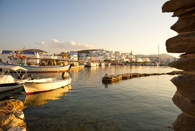 Sailboats moored at harbor against sky in city