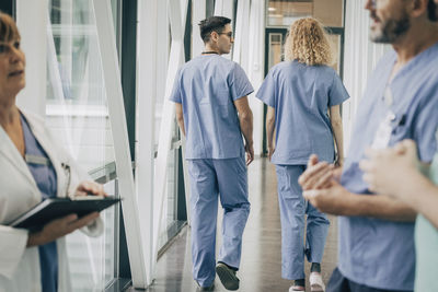 Rear view of male and female healthcare workers walking in corridor