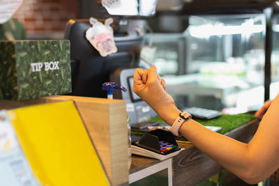 Woman paying bill through smartwatch using nfc technology in cafe