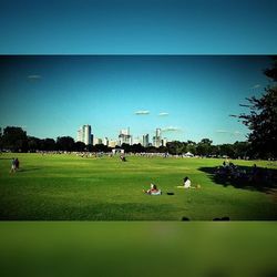 People on grassy field against clear sky