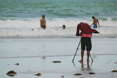 Rear view of man photographing at beach