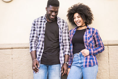 Happy couple standing against wall