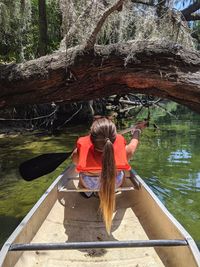 Rear view of woman sitting in boat at lake