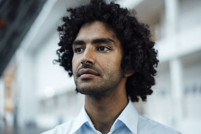 Thoughtful young male entrepreneur looking away at workplace