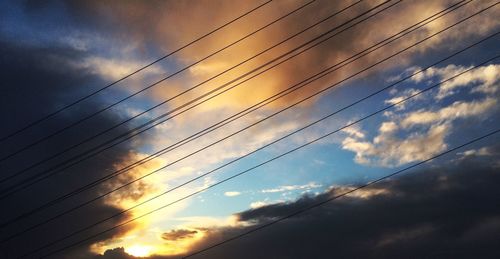 Low angle view of electricity pylon against cloudy sky