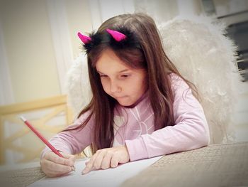 Girl wearing horned headband while studying at home