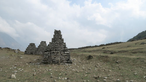 Old ruins on field against cloudy sky