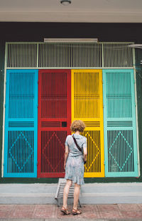 Full length of woman walking against multi colored doors