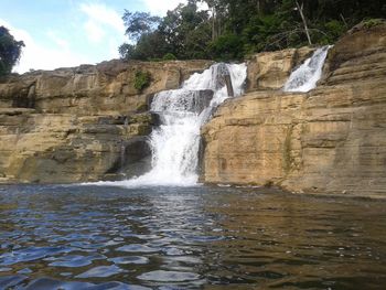 Scenic view of waterfall against sky