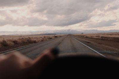 Cropped image of woman driving car while road seen through windshield