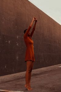 Full length of young woman standing against wall