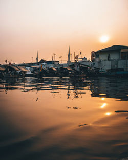 Boats moored in harbor at sunset