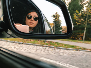 Young woman seen in rear-view mirror while sitting in car