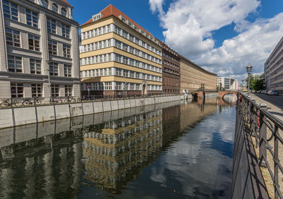 Bridge over canal amidst buildings in city against sky