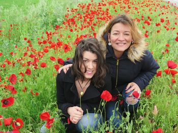Portrait of happy mother with daughter amidst poppies on field