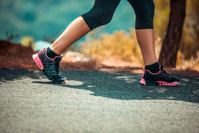 Low section of woman walking on road