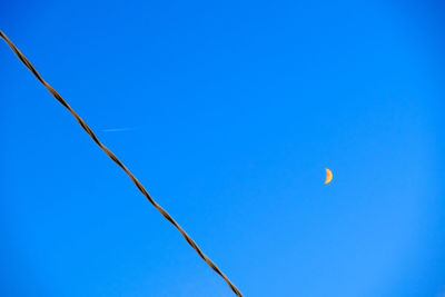 Low angle view of moon against clear blue sky