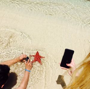 Midsection of man photographing with mobile phone at beach