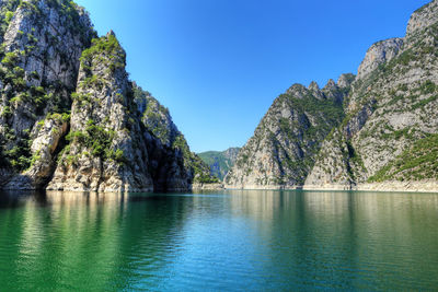 Scenic view of lake and mountains against clear blue sky