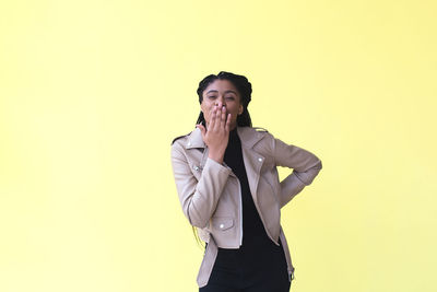 Young man standing against yellow background