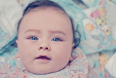 Portrait of cute baby girl lying on bed