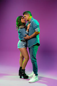 Full length of couple standing against pink background