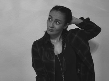 Young woman with braided hair making face while standing against wall