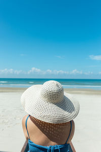 Man wearing hat on sand at beach against sky