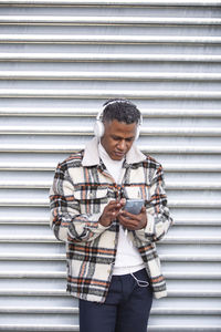 Portrait of young man standing against wall