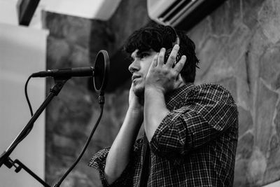 Low angle view of mid adult man singing in recording studio