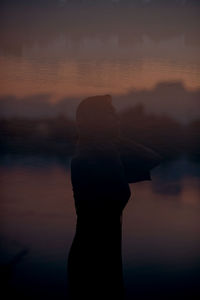 Silhouette woman standing against sky during sunset