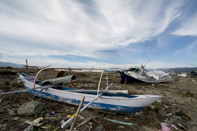 Abandoned boats moored on shore against sky